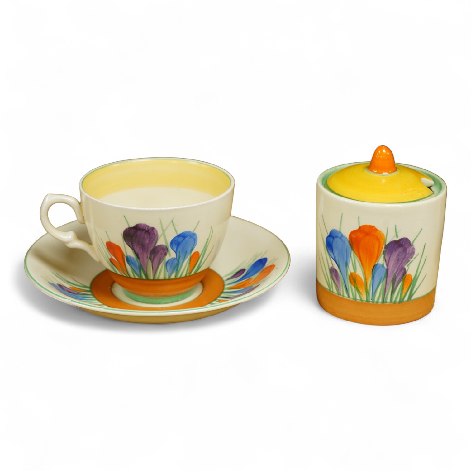 A Clarice Cliff ‘crocus’ pattern preserve jar and cover, 10cm high and a similar cup and saucer